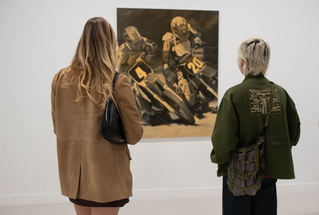 people standing in front of a painting of two people on motocross bikes