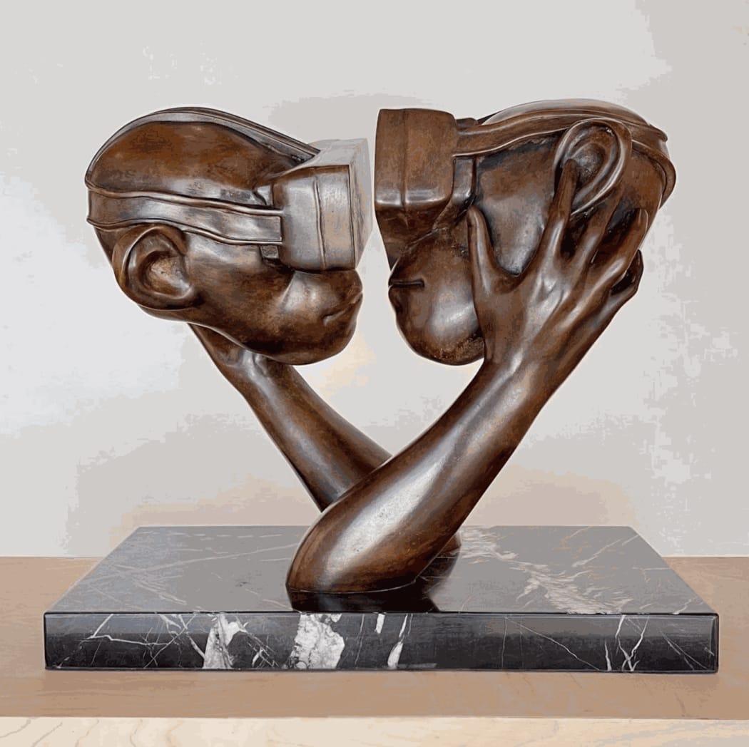 Beto Gatti's bronze sculpture “Realidade Virtual,” of two busts of people with their hands on one another's face wearing futuristic goggles.
