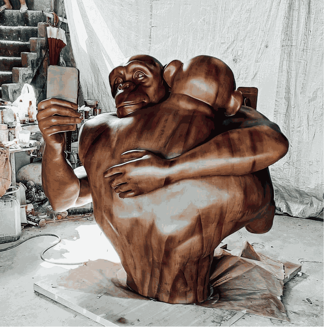 Beto Gatti's sculpture "Saudades, A Origem," made of bronze, of two busts of monkeys intertwined holding a smartphone.