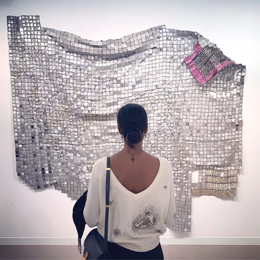 Dana Endundo Ferreira looking at artwork sculpture installation from Ghanaian artist El Anatsui at Frieze art fair london 2019. buy African contemporary and modern art online artists discover information education exhibition art diaspora