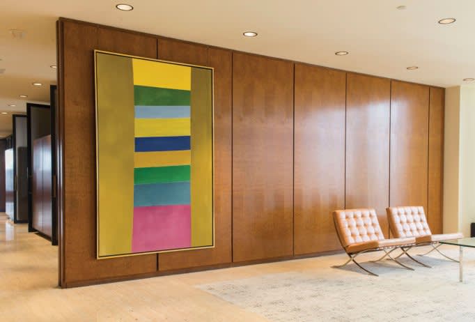 The image features a mid-century and elegant interior space. On the right, there are two identical light brown leather benches with a sleek, mid-century design, situated on a textured, off-white floor. To the left is a large abstract painting, framed in g