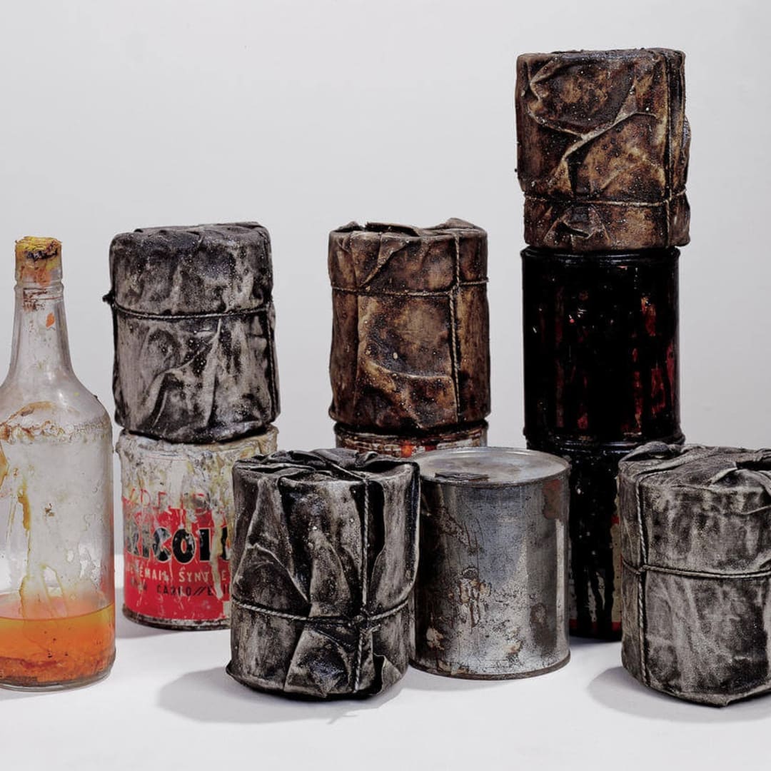 Christo Wrapped Cans, 1958-59 Group of ten cans, five wrapped, diameter of each: 4 to 4 1/8″ (10 to 10.5 cm), height of each: 4 3/4 to 5 1/8″ (12 to 13 cm), one bottle: 10 3/4 x 3″ (27 x 7.5 cm) Fabric, rope, lacquer, paint, sand, ten cans and a bottle