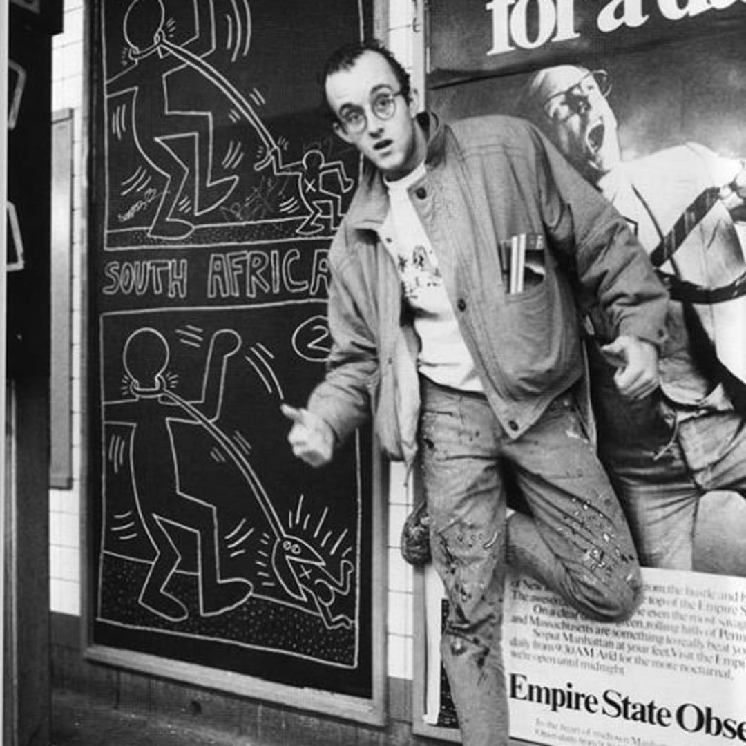 Keith Haring standing beside one of his chalk subway drawings