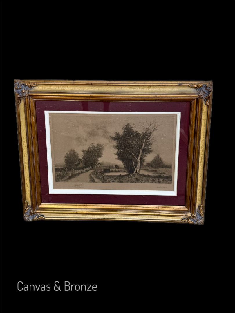 Framed sepia-toned landscape artwork depicting a rural scene with trees and a path, presented in an ornate gold frame with a burgundy mat.