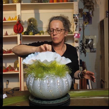 photo of the artist in her studio working on her glass blown piece
