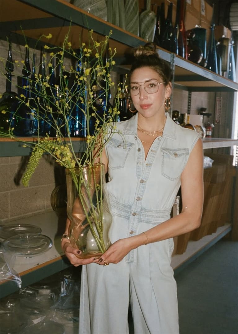 Portrait of glass artist Austin Fields holding yellow vase with tall purple flowers | represented by Kennedy Contemporary Art Gallery and Consulting