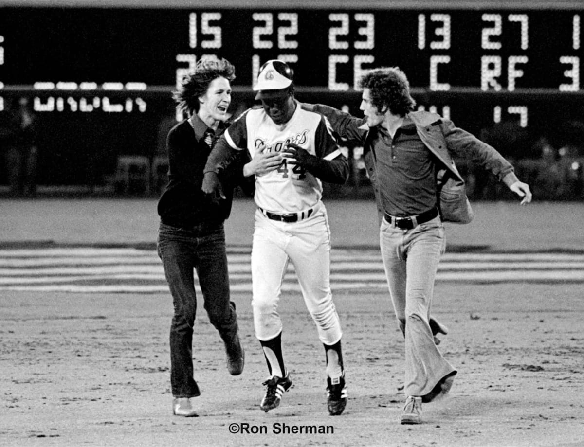 Hank Aaron (center) is congratulated on the field by teens Cliff Courtenay (left) and Britt Gaston moments after the Braves legend broke Major League Baseball's career home-run record in 1974 in a moment captured by photographer Ron Sherman. (Photo by Ron