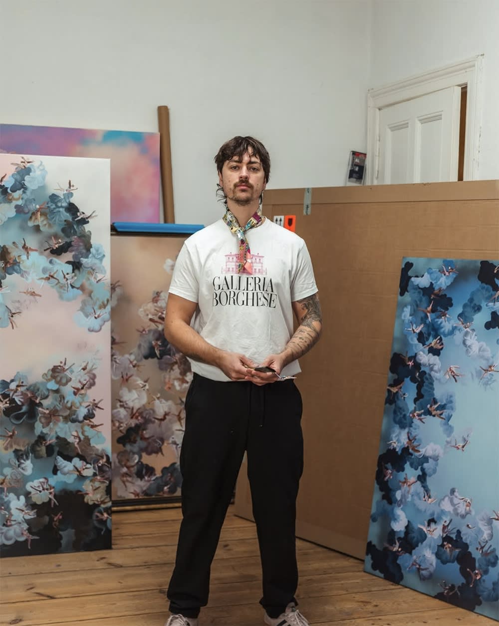 Artist Paul Kuntze in his studio with paintings in the background