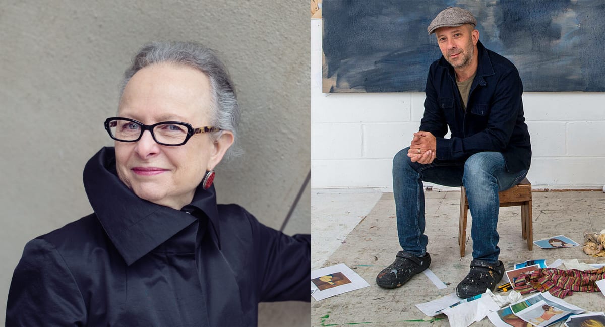 Barbara Kirschenblatt-Gimblett in black coat and glasses and Gideon Rubin sitting in in studio in clothes covered in paint