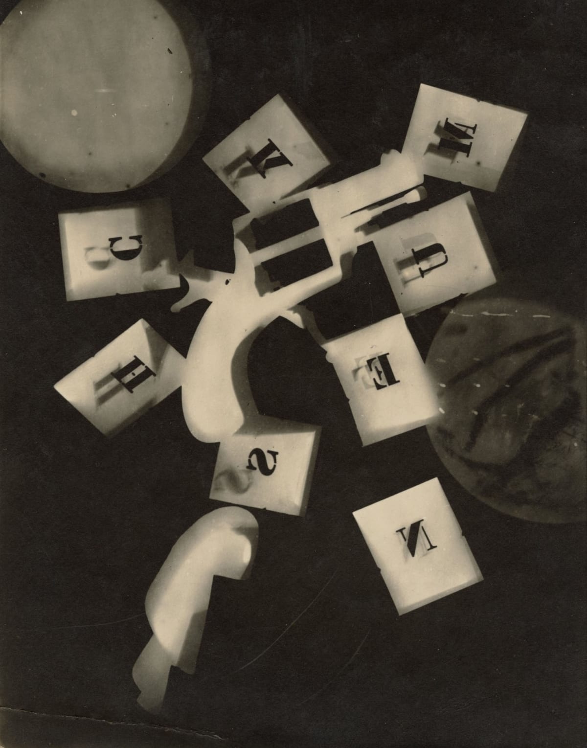 photogram of gun and stenciled letters with other unidentified geometric objects against black background by Man Ray