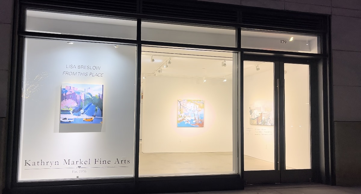 Front windows and entrance of gallery with art on the walls.
