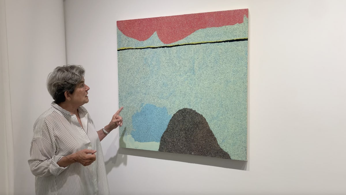 Kathryn Markel pointing to an abstract art painting.