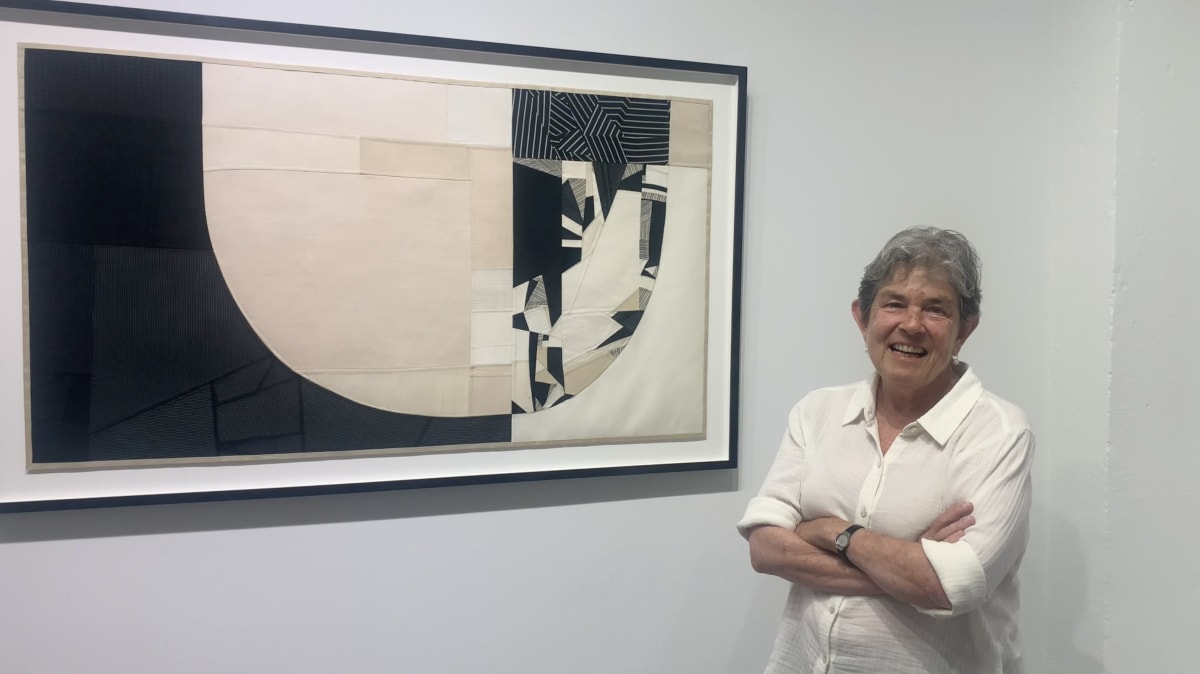 Woman standing in front of black and white collage artwork.