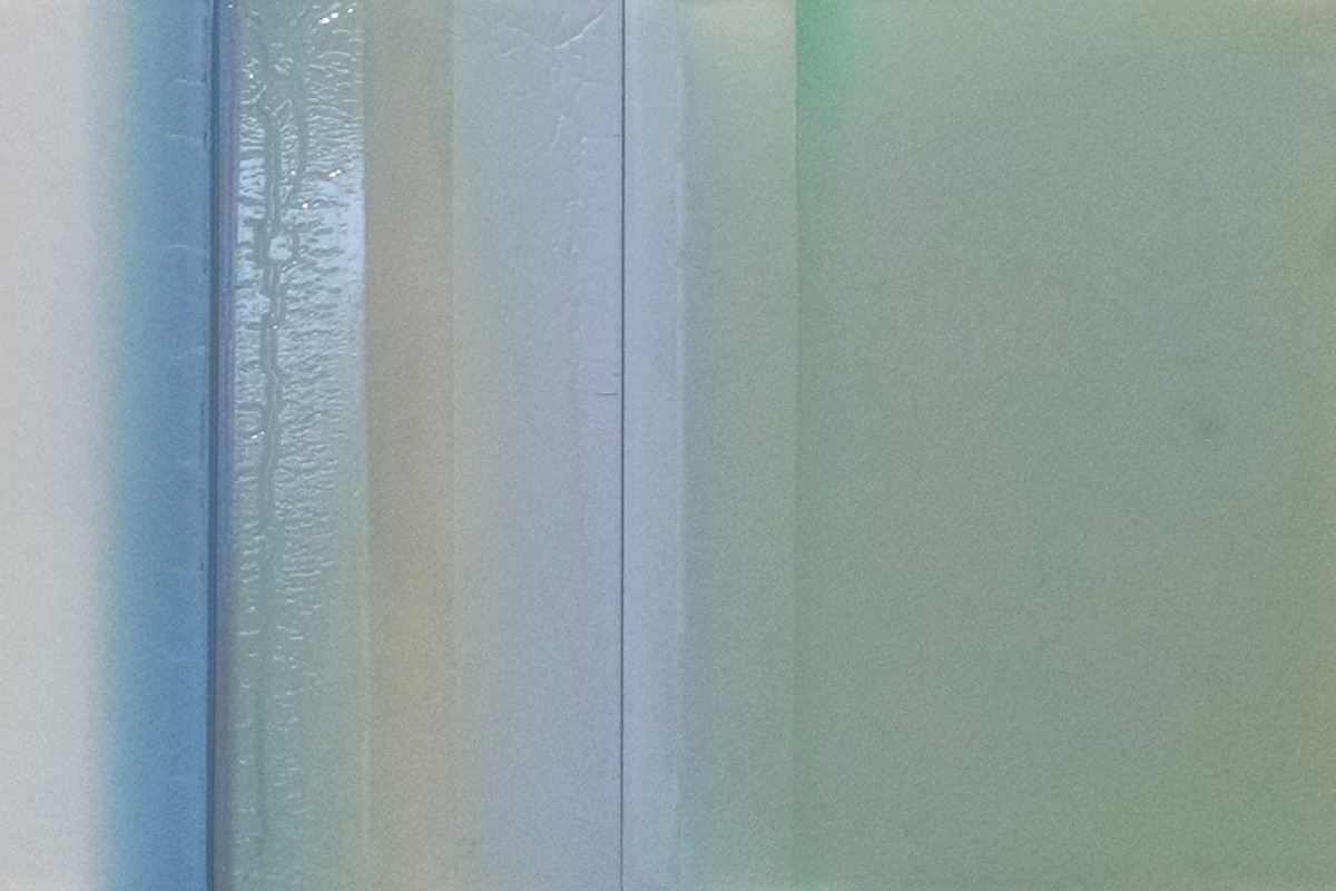 Susan English's "Blue Shade" done with tinted polymer on panel in shades of gray, tan, blue, and green. The work resembles three separate tiles in a pattern.