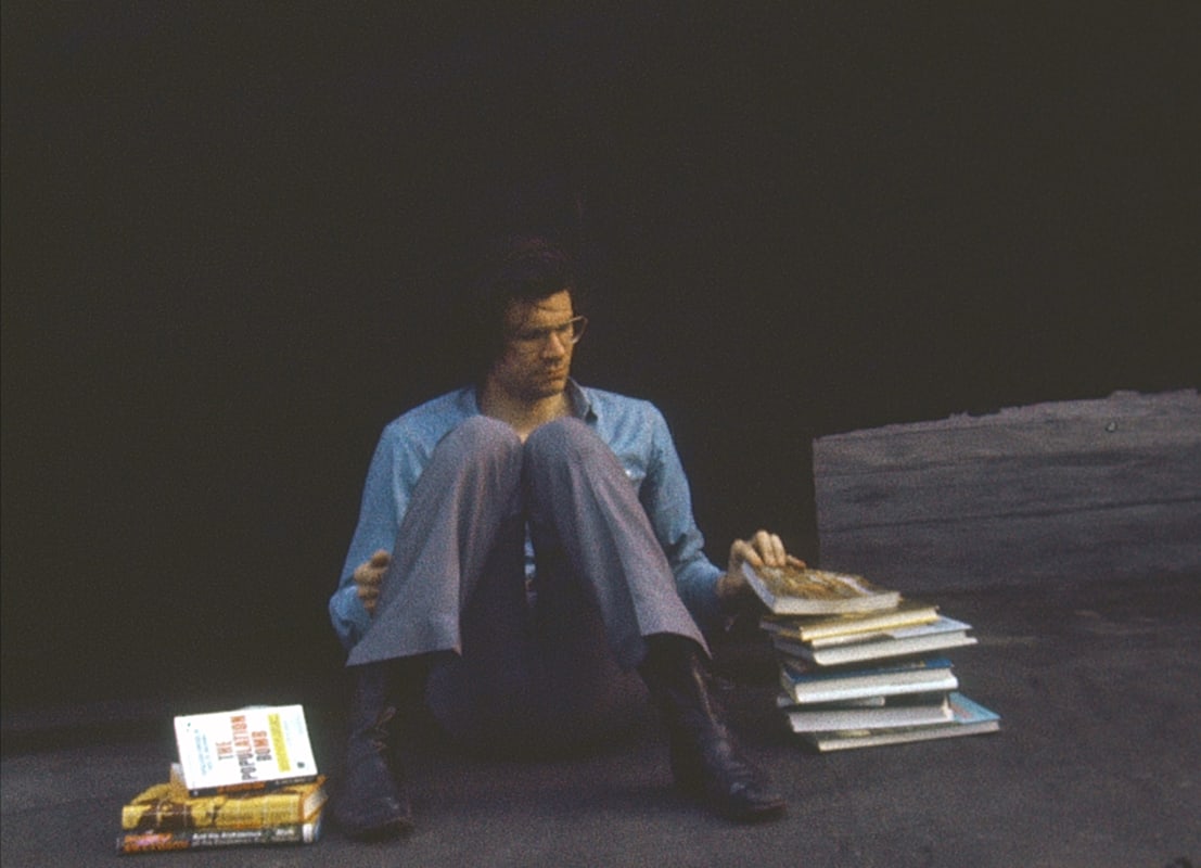 An image containing a film still of Robert Smithson with books