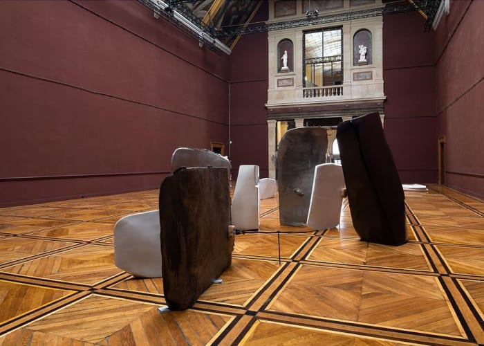 Various aluminum slabs are propped up in the center of a burgundy room.