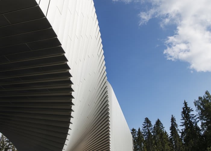 Detail image of an architectural structure with various panels in a sunny outdoor setting with trees.