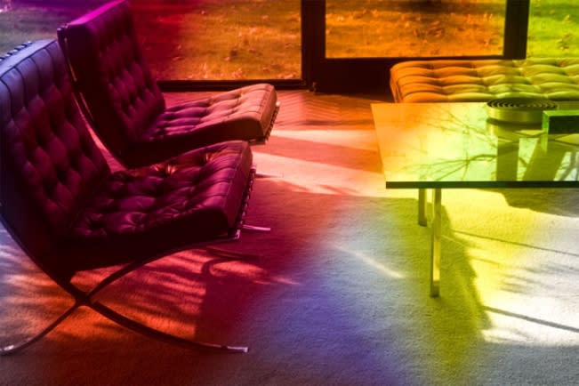 Photograph overlaid with a rainbow spectrum, depicting an interior space with two leather upholstered lounge chairs and ottoman and a glass coffee table.