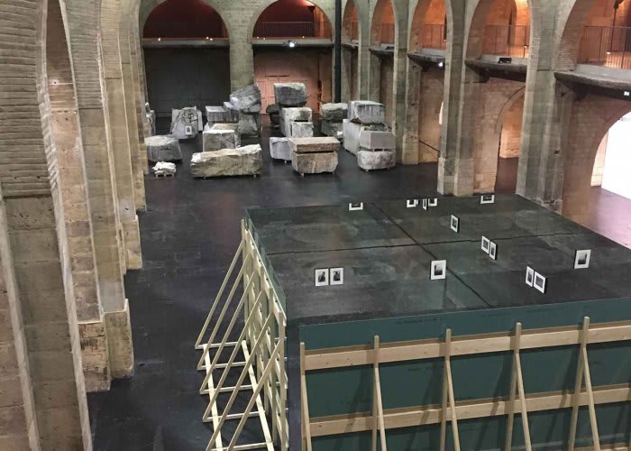 Wide angle interior image of a large stone room with various stone blocks assembled together.