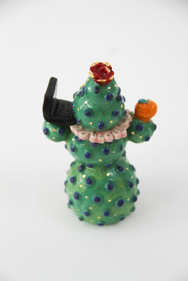 Jen Dwyer sculpture - green cactus figure with one eyeball at center holding a laptop and other accessories