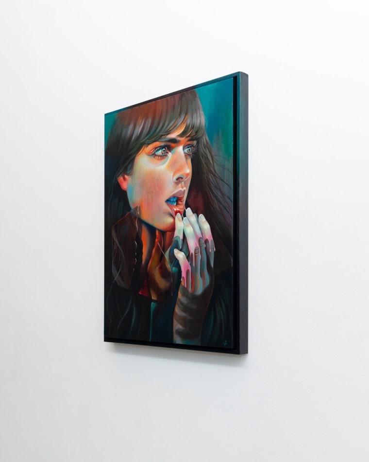 Portrait of a woman holding her hands to her bottom lip turning it out. She has long dark brown hair and eyes.