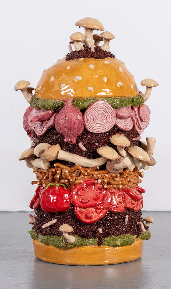 Lindsey Lou Howard sculpture of giant burger with onions, tomatoes, mushrooms, all in excessive amounts