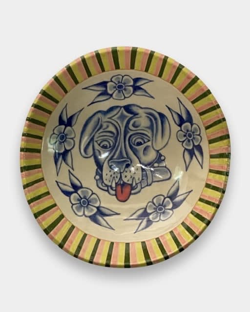 AP Shrewsbury - ceramic yellow plate with blue painted dog head in the center and five flowers circle it.