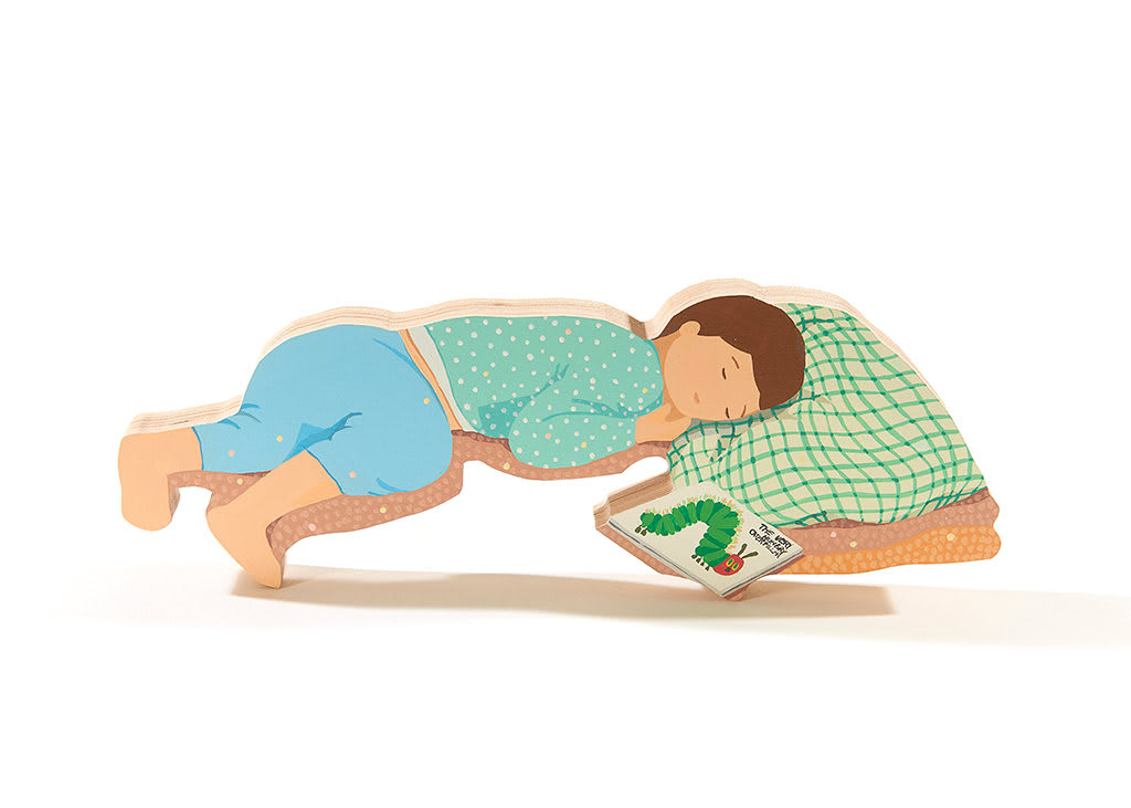 sculpture of a child laying down with the book the very hungry caterpillar next to them