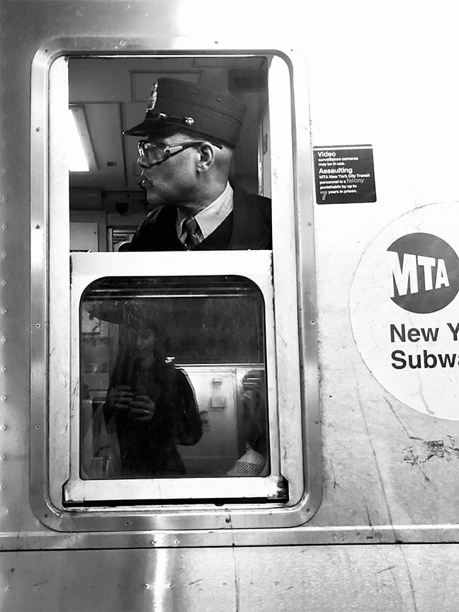 black and white photo of subway train conductor looking out window