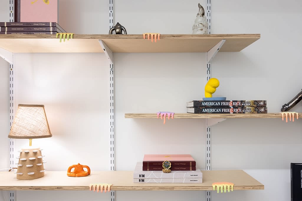 shelves with assorted books, sculptures, and lamp
