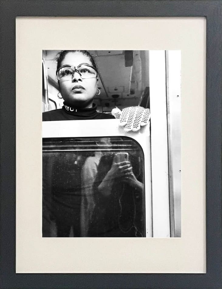 black and white photo of a subway train conductor looking out the window in black frame