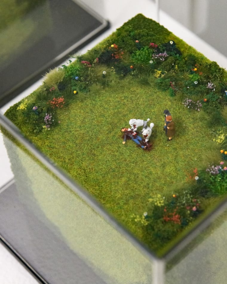 Aerial view of a miniature sculpture of two poodles eating a body by artist Abigail Goldman