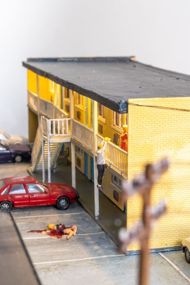 miniature diorama by Abigail Goldman of a woman bleeding on the ground in the parking lot of a motel