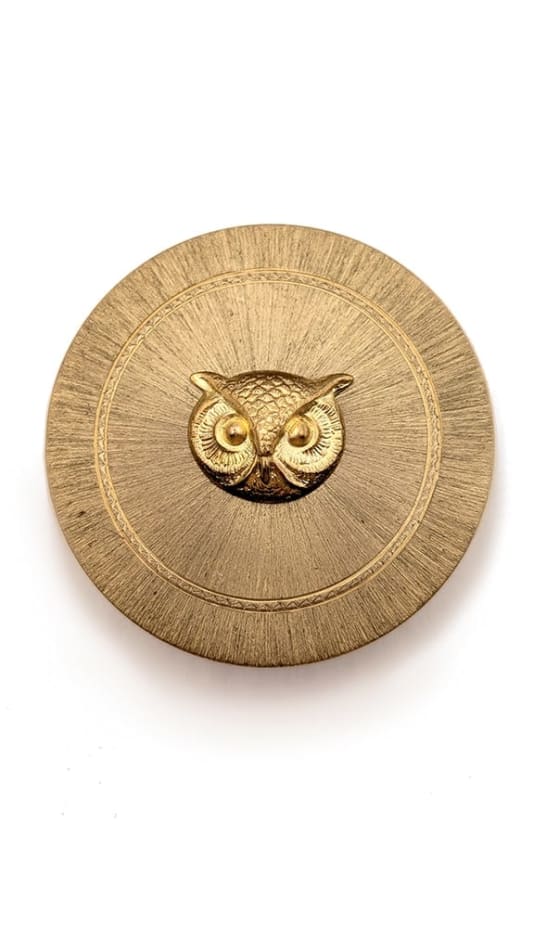 gold circular cosmetic case with gold owl face in centere
