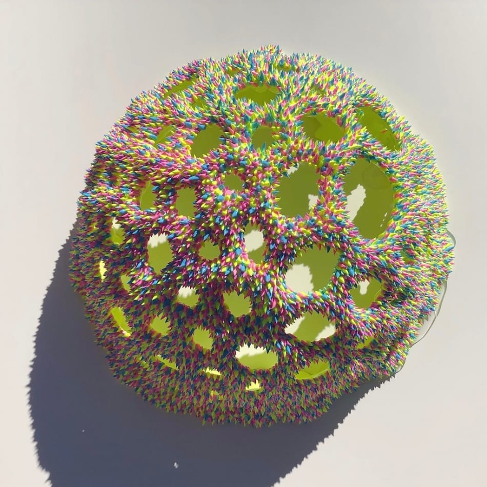 A sculpture by Dan Lam of a sphere with round holes broken through out the top of it.