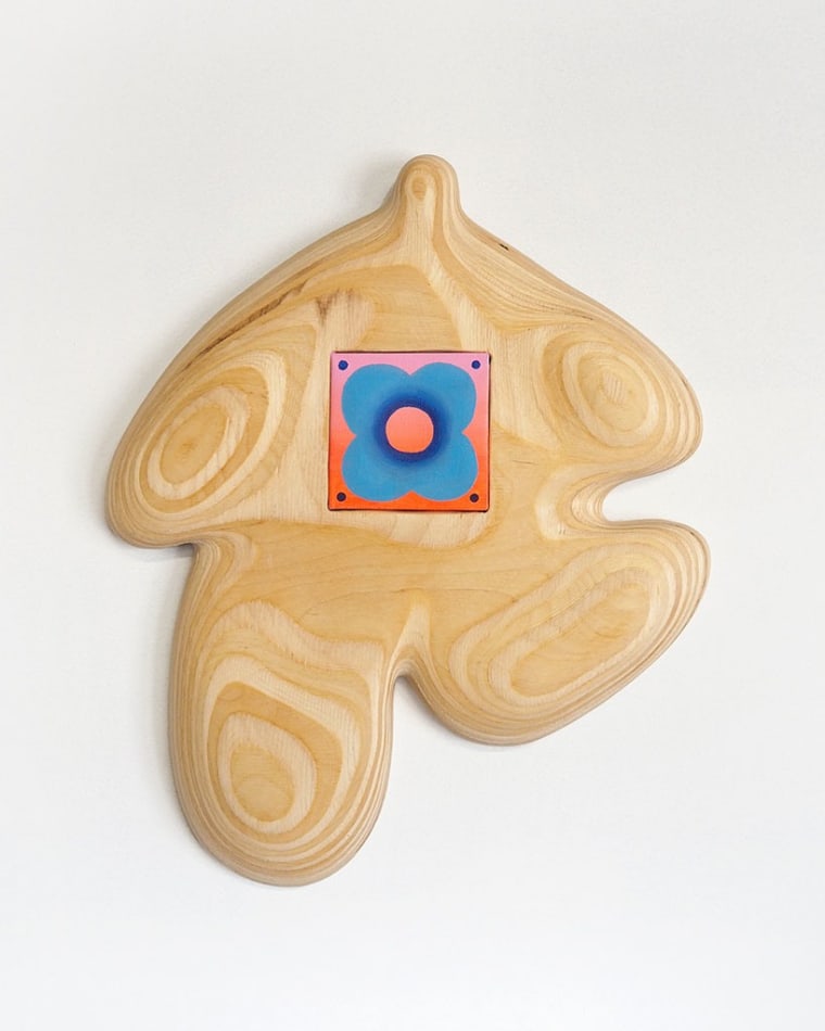 wooden figure with a small canvas in the middle with a blue flower on it