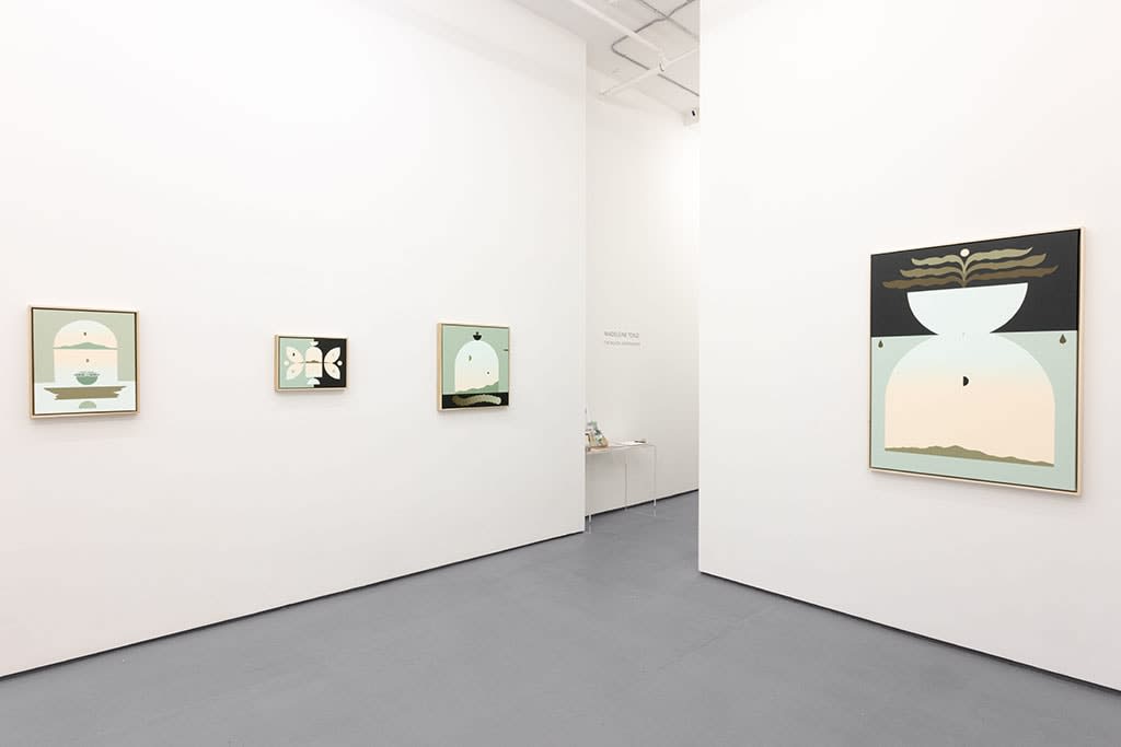 white gallery wall with four paintings in blue, black, and warm tones