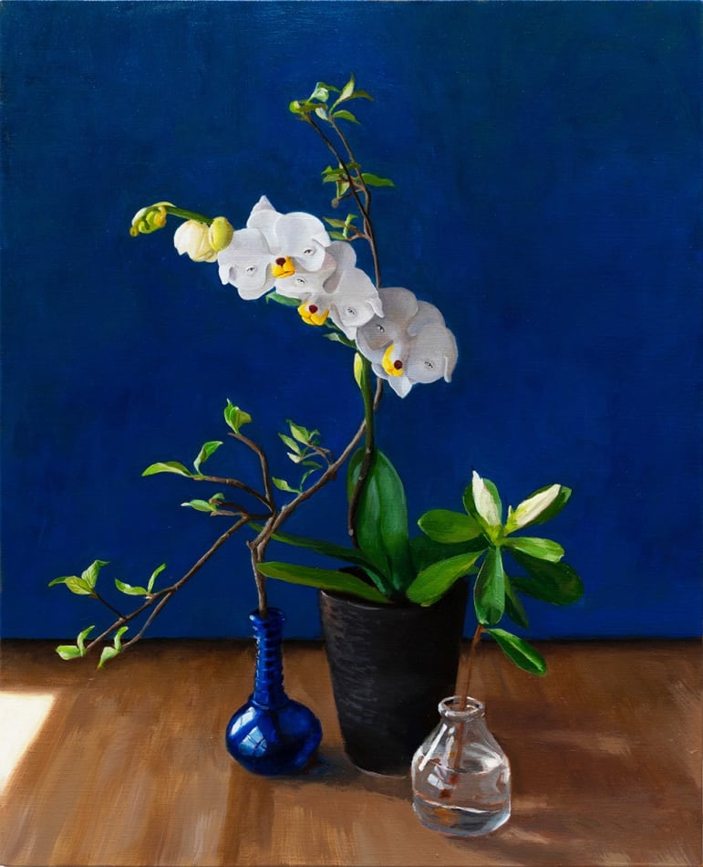 Painting of white orchids with dog faces in a small blue vase on a wooden table with a navy background