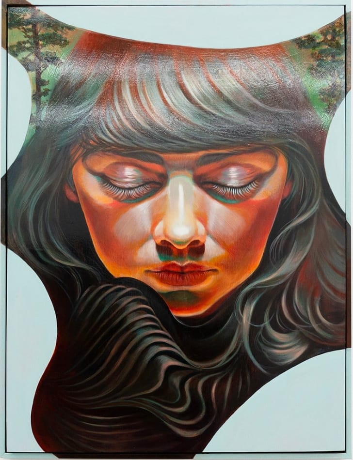 Portrait of a woman with dark brown hair and bangs facing the viewer with her eyes closed and her head turned down. There are trees in the background and an abstract blue shape creating a border around her face.