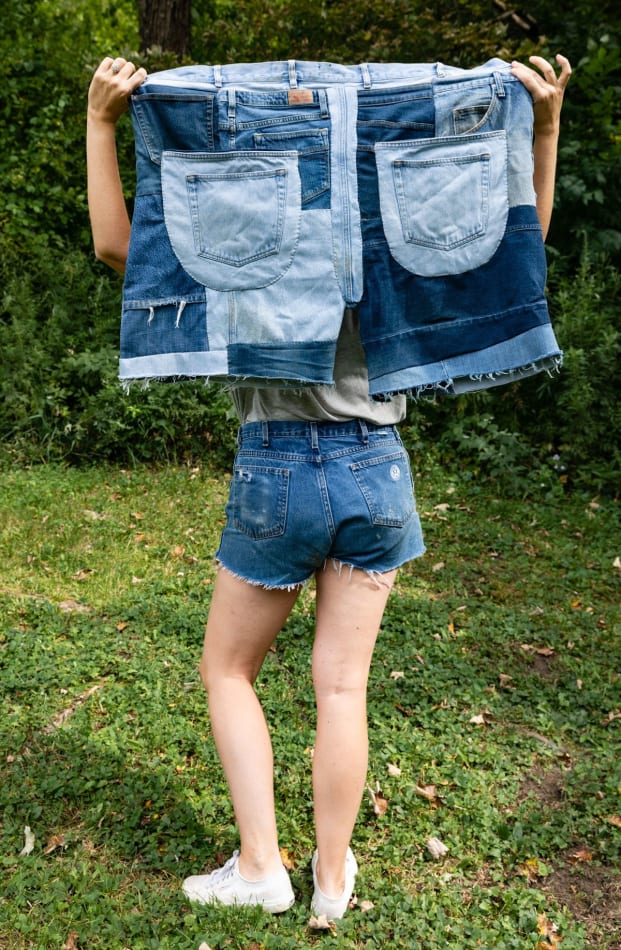 Artist Natalie Baxter holding oversized patchwork denim jorts outdoors while wearing jorts