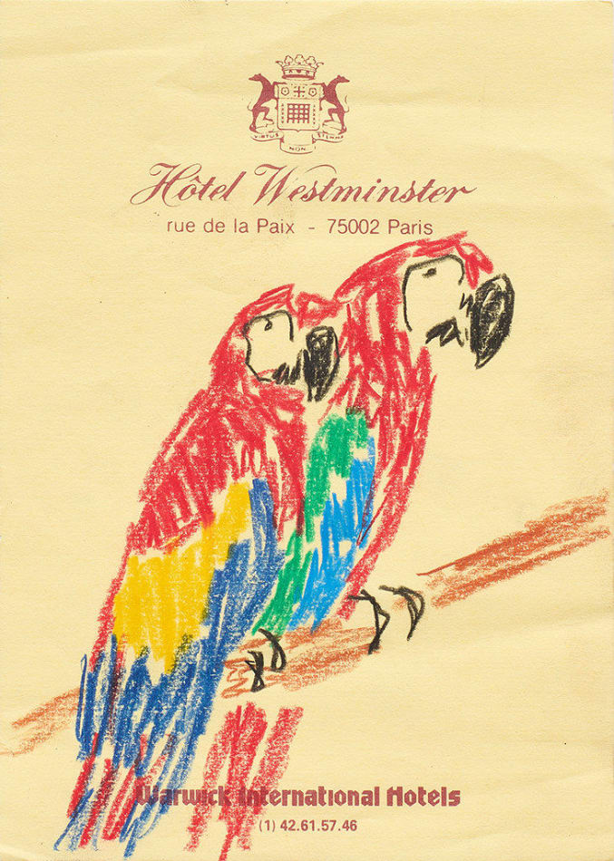 Drawing of two red parrots on a branch on yellow hotel stationery