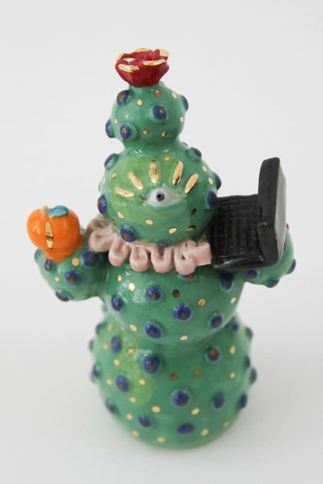 Jen Dwyer sculpture - green cactus figure with one eyeball at center holding a laptop and other accessories