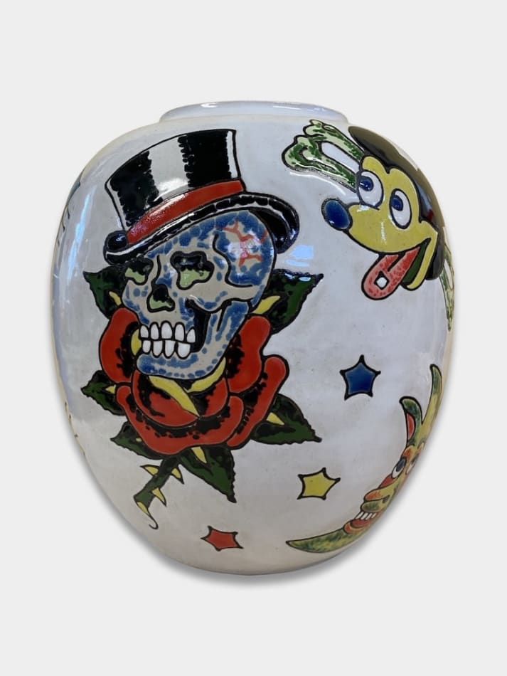white ceramic vase by artist AP Shrewsbury with a skull, mickey mouse-esque figure, and other glazed details