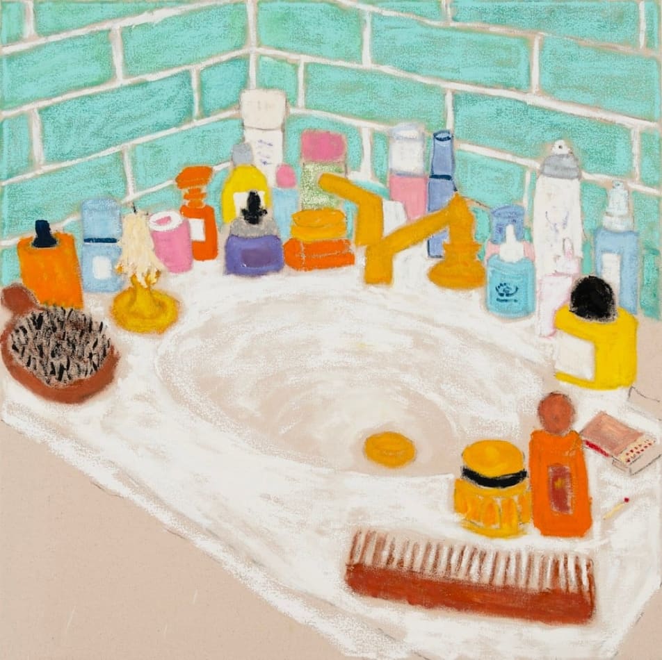 white bathroom sink countertop covered with different toiletries and blue tile behind it