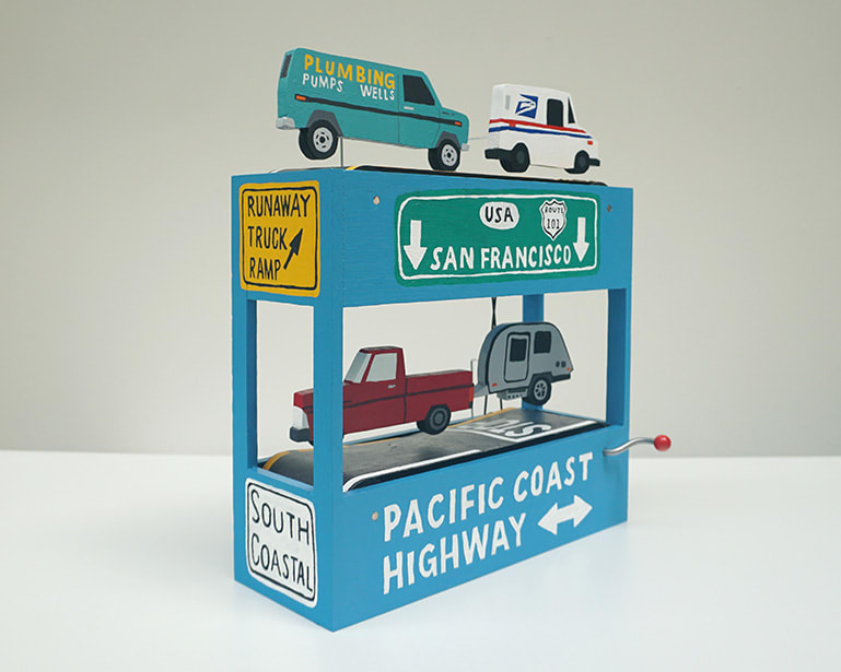 side-view of diorama-like sculpture featuring various vehicles and CA road signs by We Are Out of Office