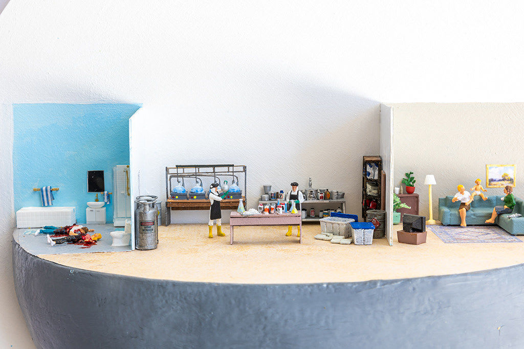miniature diorama by Abigail Goldman depicting three scenes, two people dead in a bathroom, a laboratory and a family watching tv