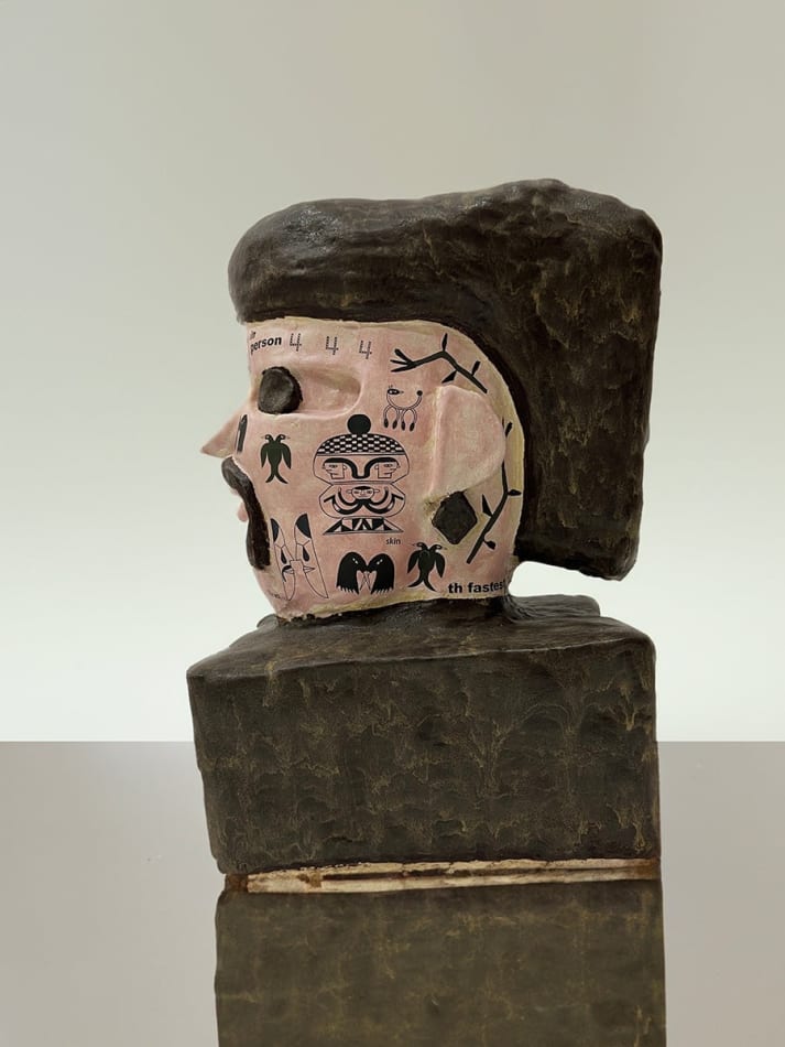 sculpture of human head with symbols all over the face