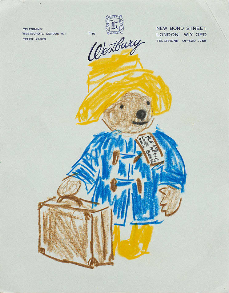 Drawing of Pattington the bear in a blue coat and yellow cap holding a brown suitcase on blue hotel stationery