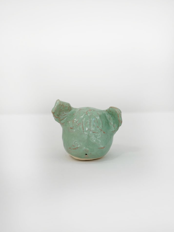 Ceramic sculpture of a the artists dog head in a mint green glaze