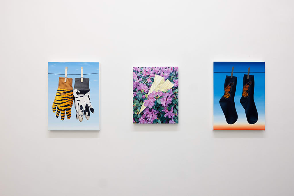 White gallery wall with three different paintings by Sara Suppan